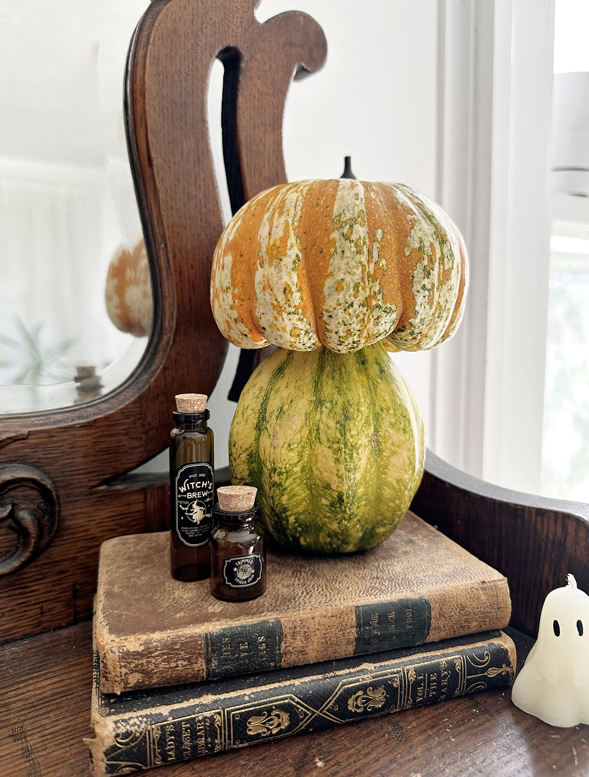 stacked pumpkins to look like mushroom set on top of vintage books next to amber potion vials
